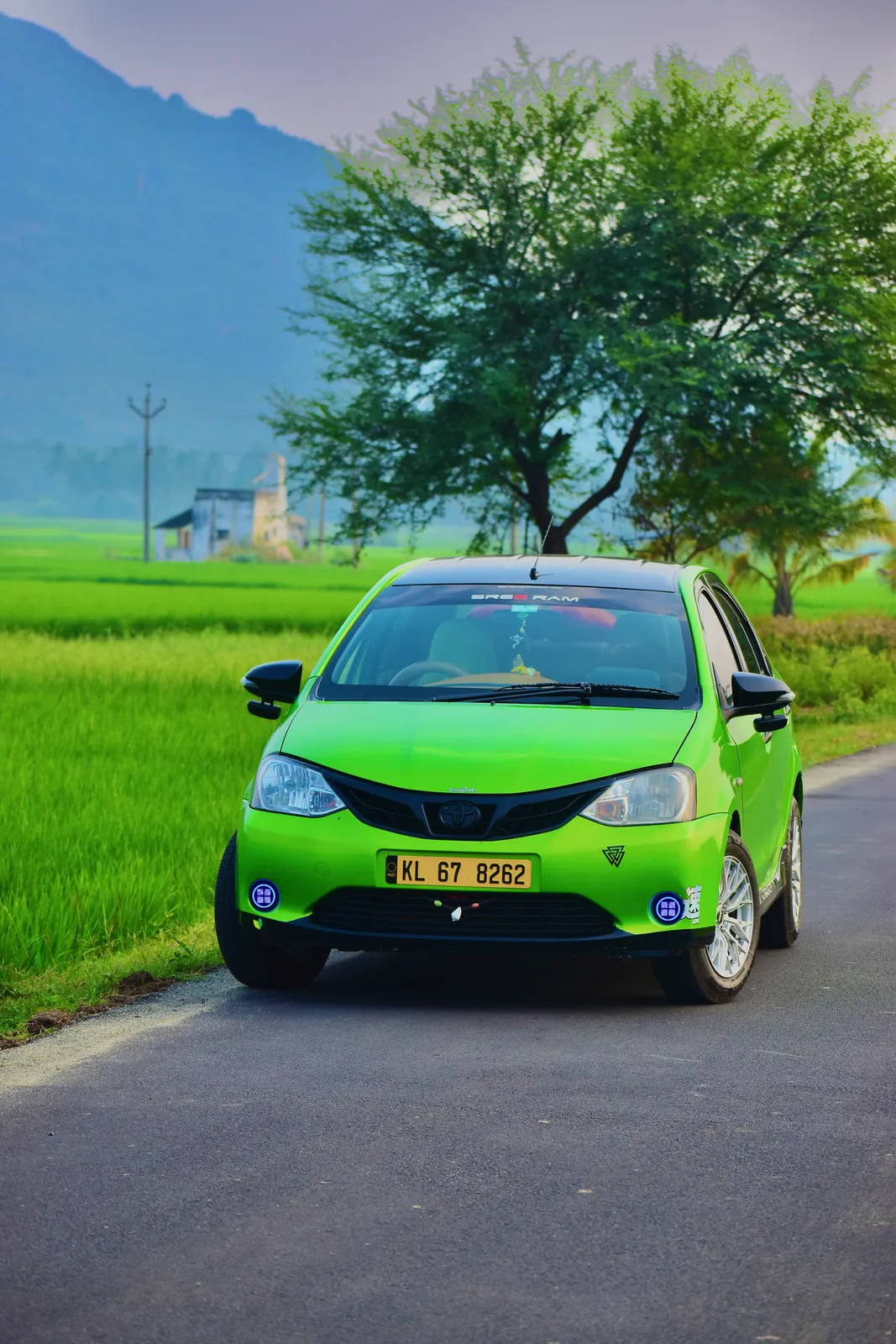 Munnar Trip Makers taxi on a country road beside green paddy fields