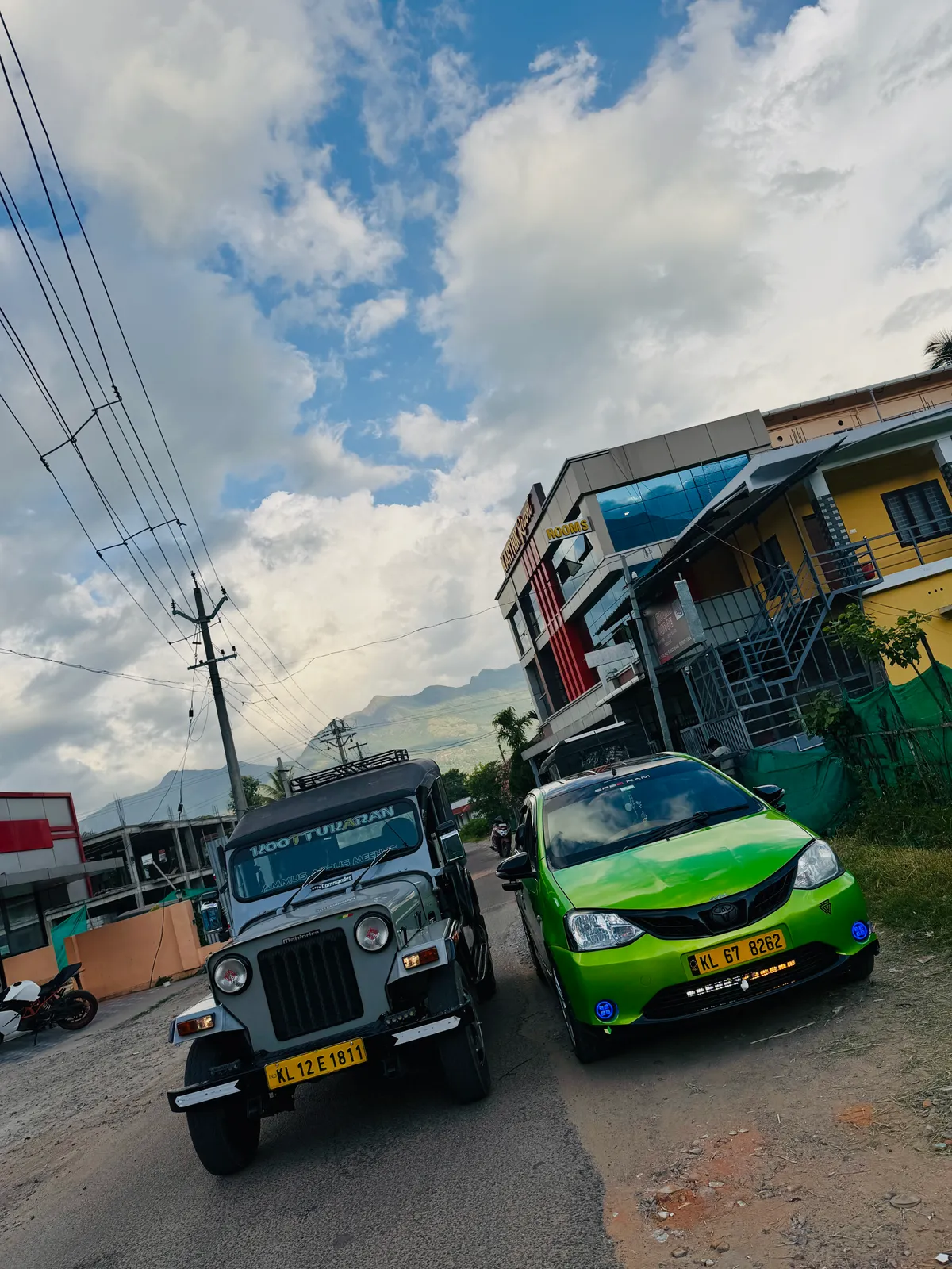 A safari jeep and a green cab waiting together at a Munnar roadside pickup